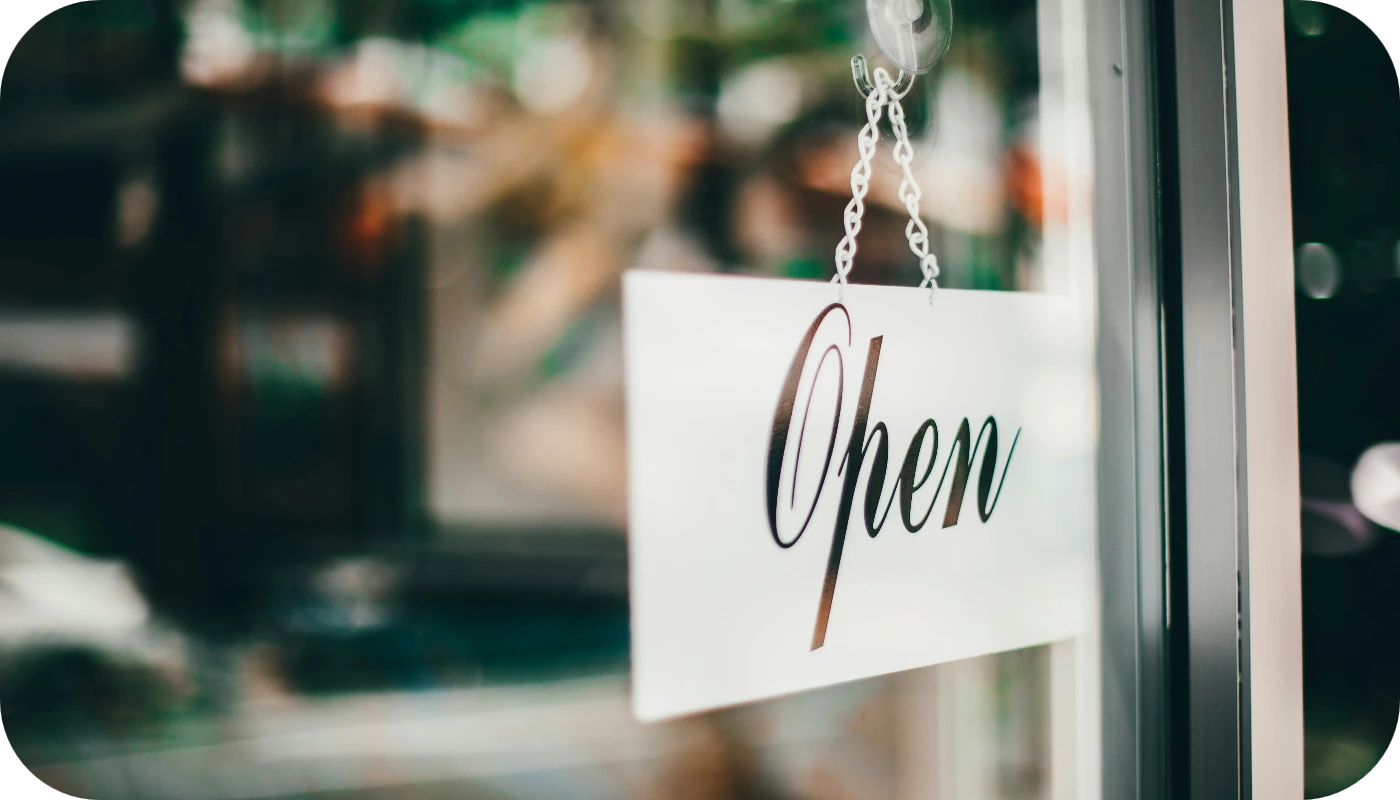 Cartel de "Open" colgado en puerta de cristal de negocio