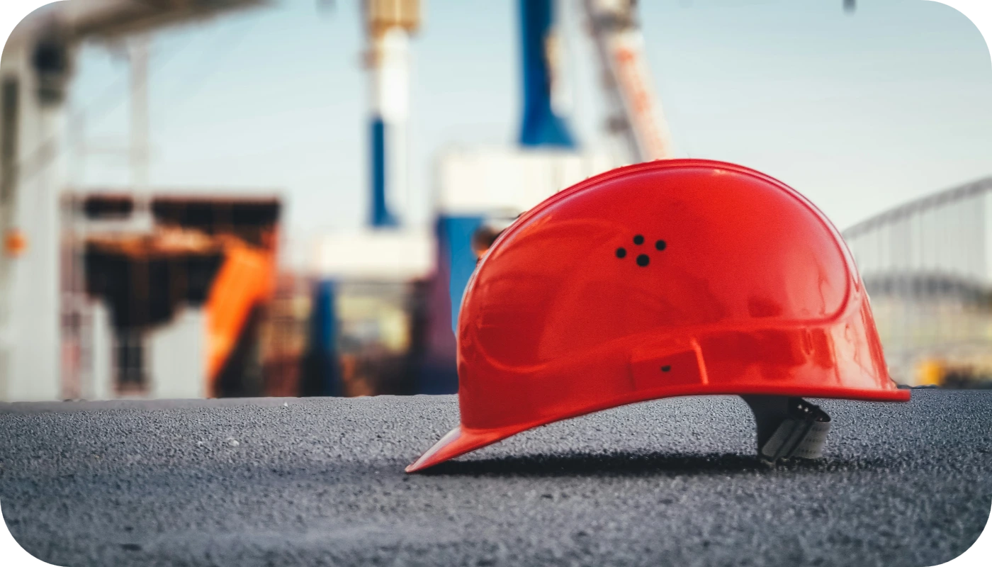 Casco de seguridad rojo en obra con grúas al fondo
